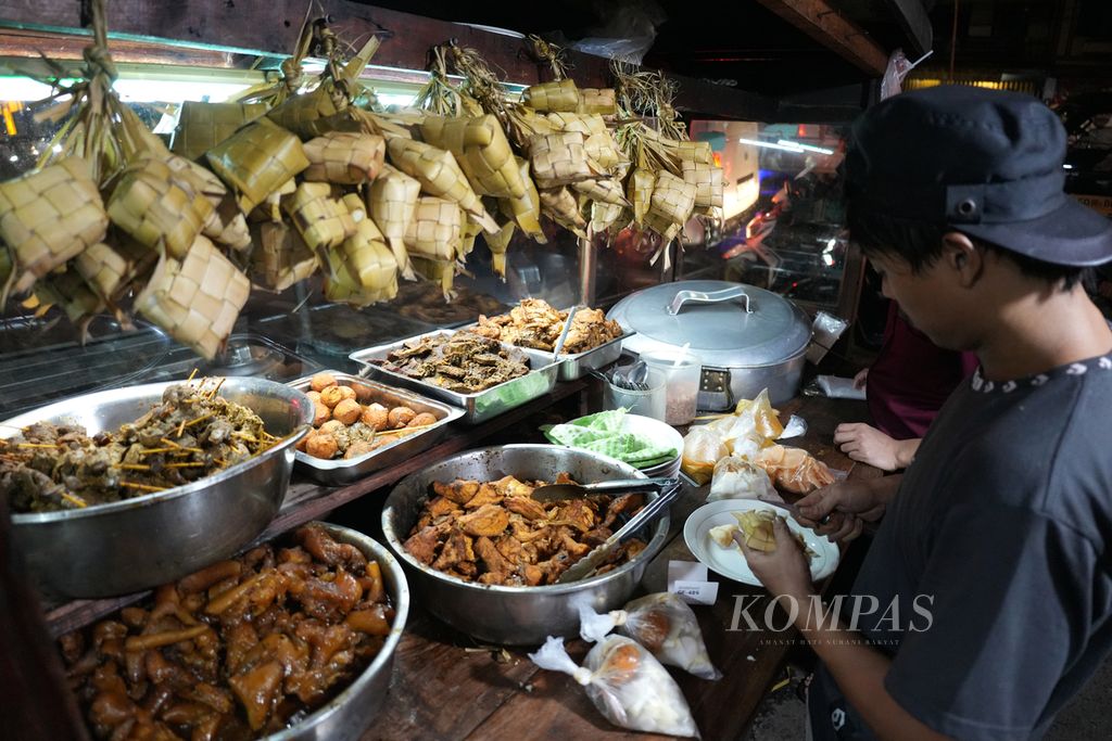 Penjual melayani pembeli Ketupat Sayur Mandala di Jalan Mampang Prapatan, Jakarta Selatan, Rabu (13/11/2024). Warung ketupat sayur tersebut buka dari pukul 18.00 WIB hingga pukul 04.00 WIB. Dalam sehari sebanyak 600-700 porsi habis terjual. Ada enam pilihan menu ketupat sayur di warung tersebut. 