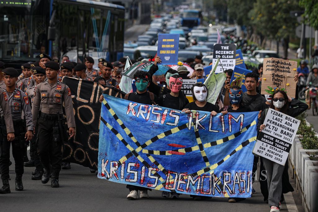 Peserta aksi membentangkan poster dan spanduk saat <i>long march</i> di Jalan Jenderal Sudirman, Jakarta, Jumat (27/9/2024). 