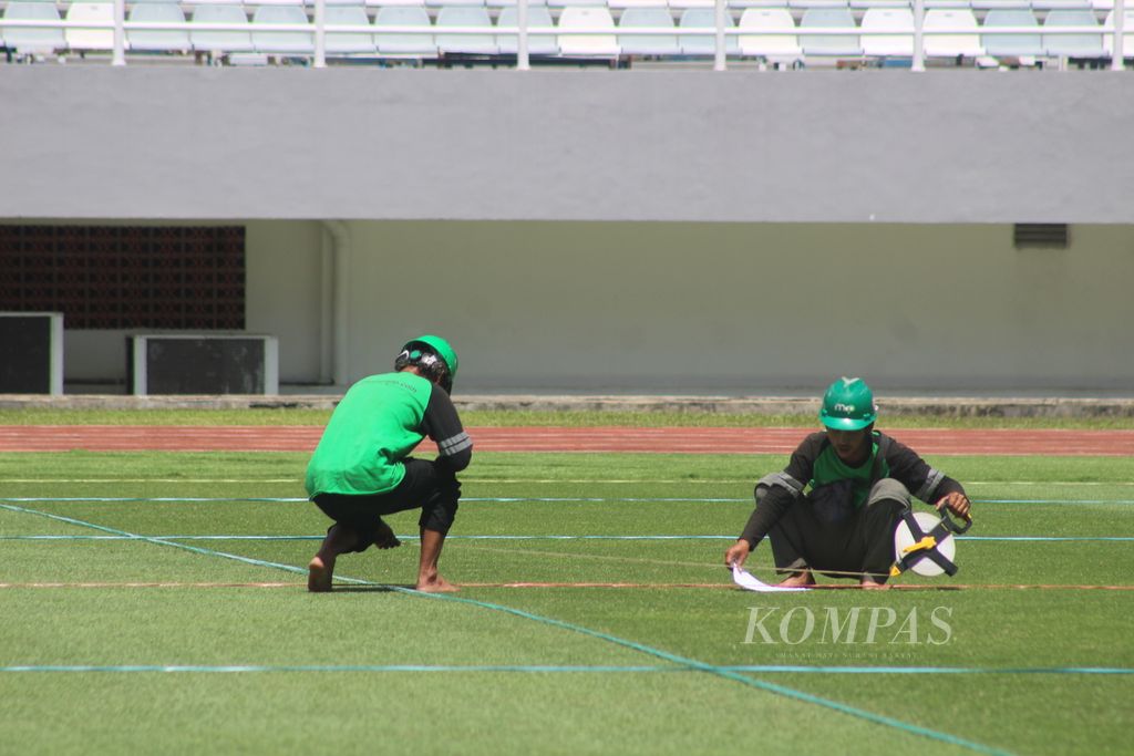 Dua petugas sedang memelihara rumput di Stadion Gelora Sriwijaya Palembang, Sumatera Selatan, Sabtu (11/3/2023). Sejumlah pembenahan dilakukan agar stadion berkapasitas 23.000 penonton ini bisa memenuhi stadardisasi FIFA. 