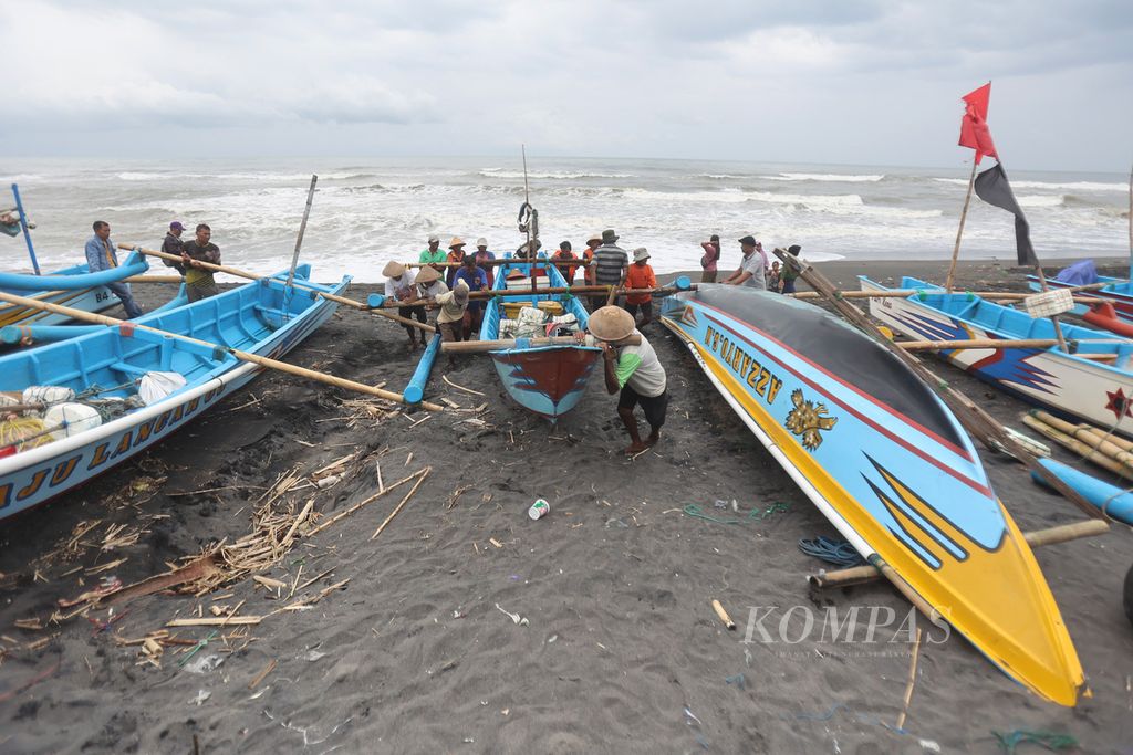 Nelayan membantu rekannya menepikan perahu yang digunakan untuk mencari ikan di Pantai Depok, Bantul, DI Yogyakarta, Kamis (9/2/2023). Sebagian kecil nelayan di pantai itu tetap memberanikan diri melaut meski tengah berlangsung gelombang tinggi dan berbahaya terhadap keselamatan mereka. Siklon tropis Freddy yang berlangsung di kawasan selatan Jawa memicu hujan lebat, angin kencang, dan gelombang tinggi di sejumlah kawasan.