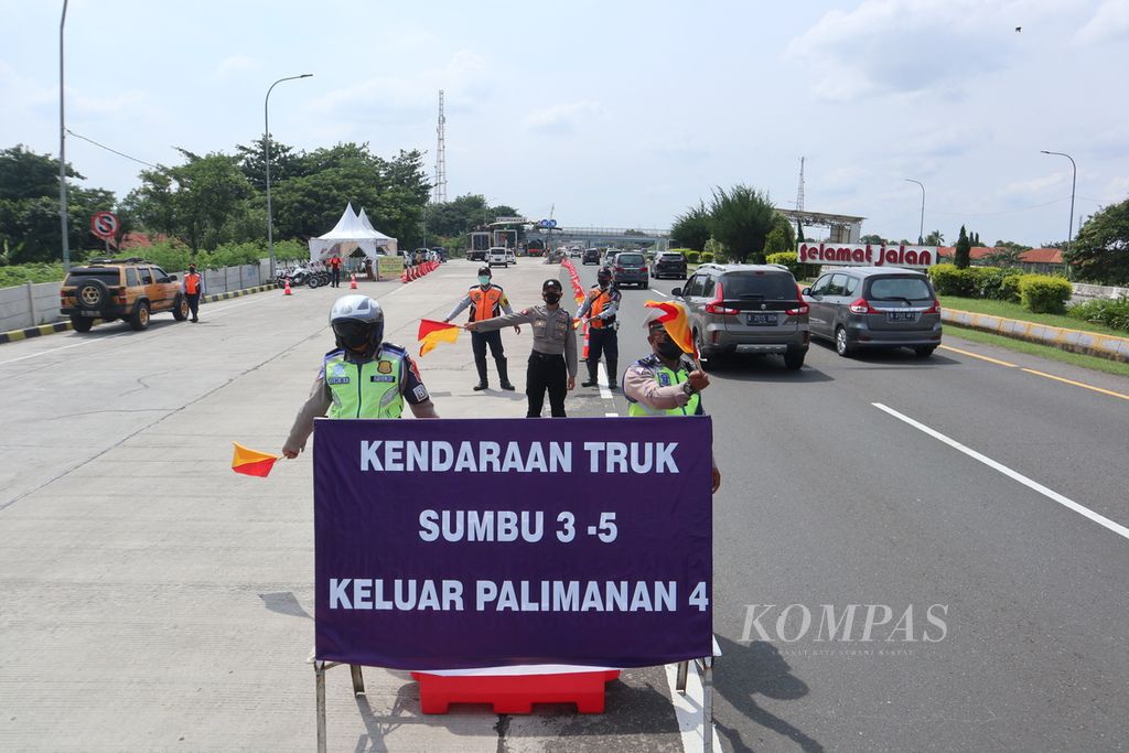 Petugas berjaga untuk mengarahkan truk keluar Gerbang Tol Palimanan 4, Kabupaten Cirebon, Jawa Barat, Minggu (2/1/2022). Kendaraan dengan sumbu tiga ke atas yang mengarah ke Jakarta harus keluar tol untuk mengantisipasi lonjakan volume kendaraan pada puncak arus balik.