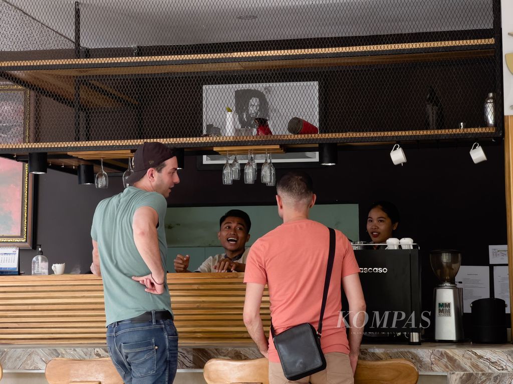 Dua karyawan di restoran JM Hotel Kuta, Pujut, Lombok Tengah, Nusa Tenggara Barat, Senin (25/7/2022), berbincang dengan wisatawan asing yang datang berlibur ke kawasan tersebut. Seiring makin menggeliatnya kawasan Mandalika, masyarakat juga tak ingin sekadar menonton dan saat ini mulai mengambil bagian.