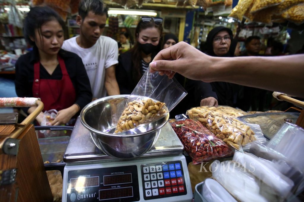 Karyawan kios Satu Hati yang menjual aneka camilan, termasuk kacang mete, di Pasar Jatinegara, Jakarta Timur, melayani pembeli, Kamis (4/4/2024).