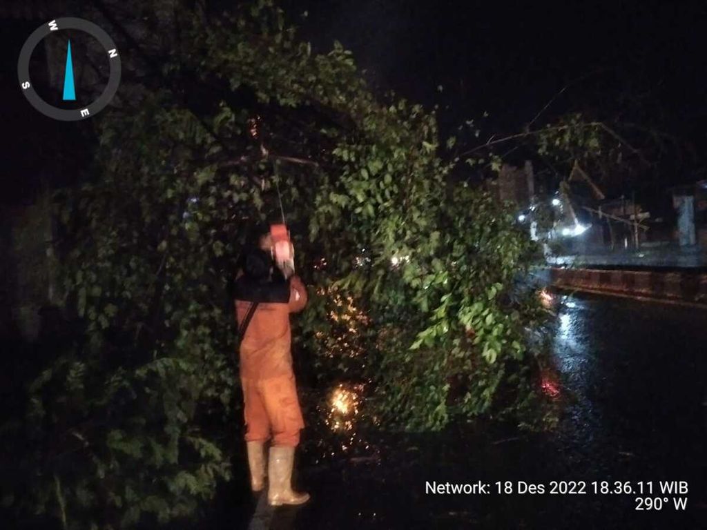 Petugas memotong pohon yang tumbang di Kabupaten Cirebon, Jawa Barat, Minggu (18/12/2022).