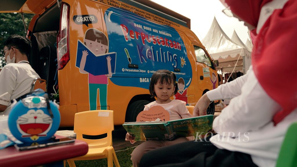 Seorang anak membaca buku dari perpustakaan keliling yang meramaikan pencanangan HUT Ke-495 Jakarta di Taman Lapangan Banteng, Jakarta Pusat, Rabu (24/5/2022). Selain bazar UMKM, acara untuk memeriahkan HUT Jakarta pada 22 Juni mendatang ini juga diisi penampilan musik, kegiatan vaksinasi penguat, dan bercerita untuk anak-anak.