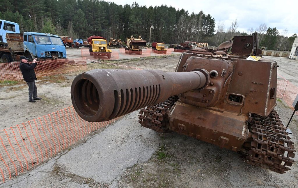 Seorang pengunjung mengabadikan deretan kendaraan alat berat, termasuk kendaraan lapis baja yang digunakan dalam pekerjaan pemulihan setelah kecelakaan di pembangkit listrik Chernobyl, di kota hantu Pripyat, Ukraina, Sabtu (24/4/2021).