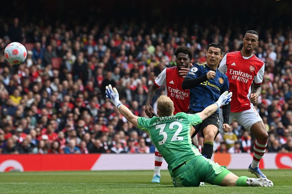 Penyerang MU Cristiano Ronaldo menendang bola di depan penjaga gawang Arsenal Aaron Ramsdale yang menjadi gol satu-satunya bagi MU dalam pertandingan lanjutan Liga Inggris antara Arsenal dan MU di Stadion Emirates, London, Sabtu (23/4/2022).