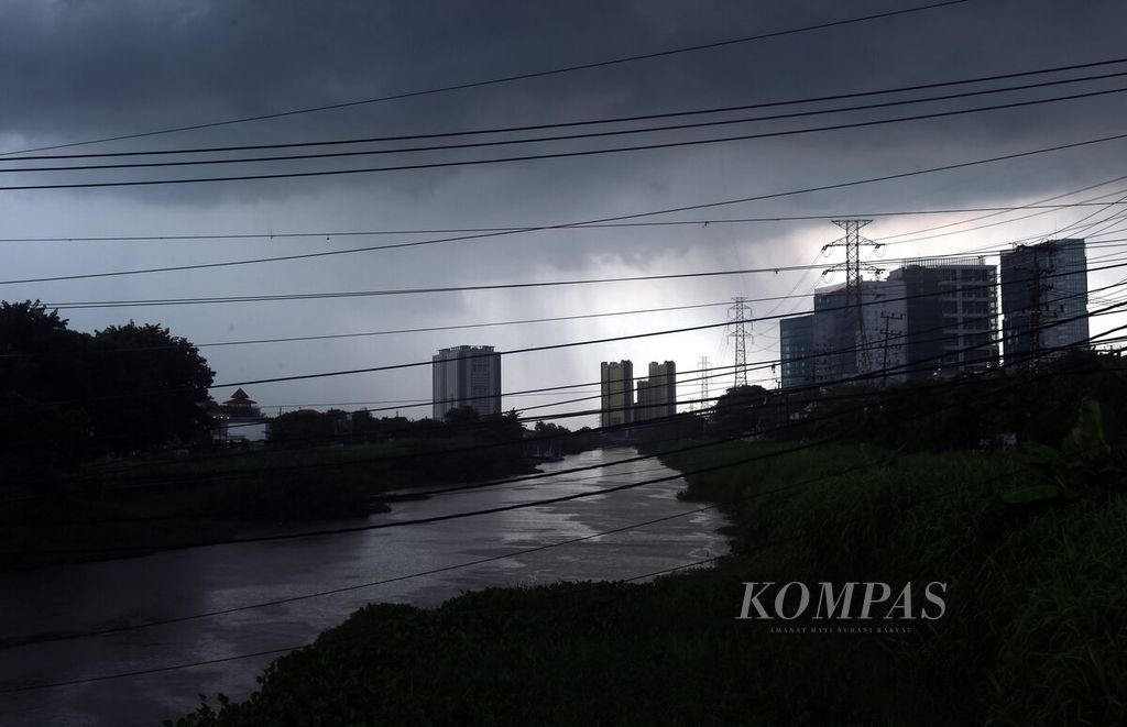 Gedung bertingkat saat awan hitam terbentuk di langit Surabaya, Jawa Timur, Jumat (19/1/2024).  