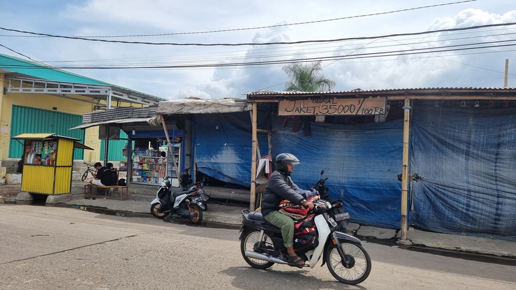 Warga melintasi kios penjualan baju bekas yang ditutup di Pasar Gedebage, Kecamatan Panyileukan, Kota Bandung, Jawa Barat, Selasa (21/3/2023).