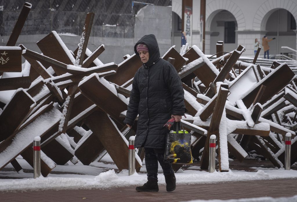 Seorang perempuan warga Ukraina berjalan di depan barikade antitank di pusat kota Kyiv, Ukraina, Senin (12/12/2022). Presiden Ukraina Vladymyr Zelenskyy kembali menyerukan agar militer Rusia menghentikan invasinya dan segera meninggalkan wilayah Ukraina. (AP Photo/Efrem Lukatsky)