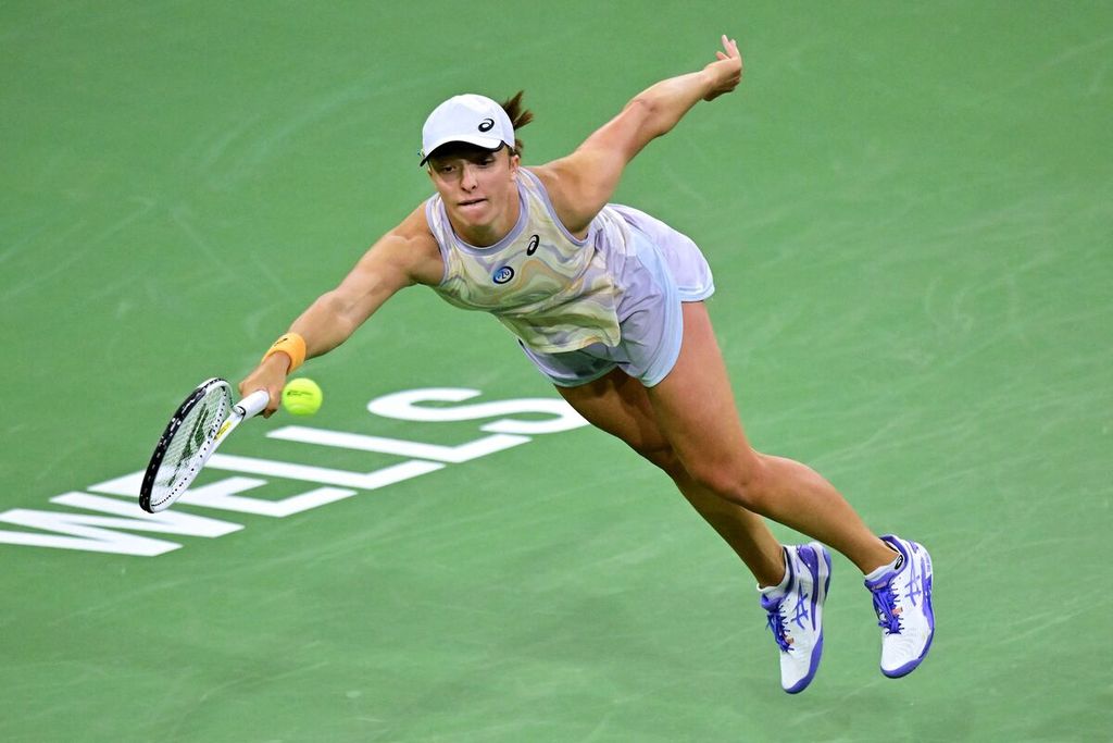 Petenis Polandia Iga Swiatek melepaskan pukulan <i>forehand</i> saat melawan petenis Inggris, Emma Raducanu, dalam pertandingan babak keempat turnamen WTA 1000 Indian Wells di Stadion 1 Indian Wells Tennis Garden, California, Amerika Serikat, Selasa (14/3/2023) malam waktu setempat atau Rabu WIB. Swiatek menang dengan skor 6-3, 6-1.