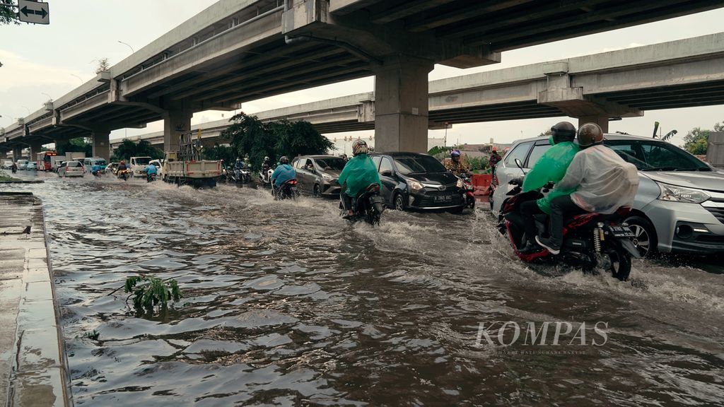 Pengguna jalan berhati-hati melintasi genangan di Jalan Raya Kalimalang, Duren Sawit, Jakarta Timur, Jumat (20/5/2022). Hujan dengan intensitas lebat dan drainase yang buruk mengakibatkan sejumlah genangan di jalan raya. 