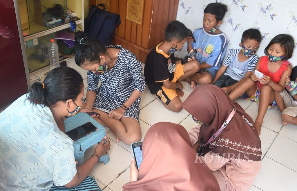 Pelajar memanfaatkan rumah warga yang terdapat Wi-Fi gratis di Jalan Kenjeran IV, Surabaya, Jawa Timur, Jumat (22/1/2021). Program Wi-Fi gratis pada Senin, Rabu, dan Jumat untuk mengurangi beban kuota internet bagi pelajar di kampung setempat dalam belajar daring. Kegiatan digagas oleh Karang Taruna Kampung Dolanan.