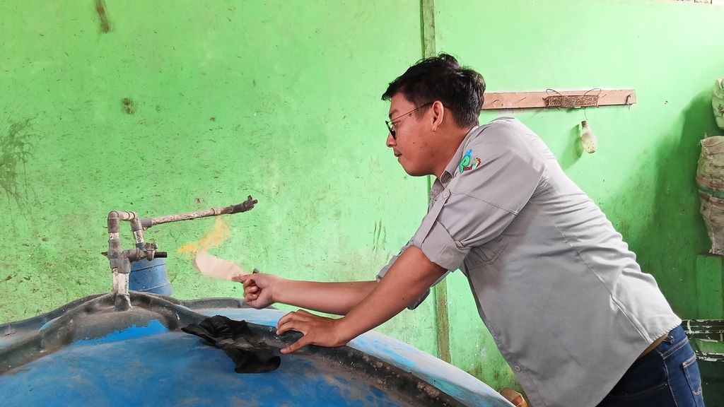 Muhamad Zulton Abdul Aziz, Ketua Yayasan Bumi Selaras sekaligus Ketua Swadaya Masyarakat Rangga Mekar Bank Sampah Rangga Mekar, saat menunjukkan pengelolaan sampah menjadi pupuk cair di TPS3R Rangga Mekar, Bogor Selatan, Kota Bogor, Kamis (31/8/2023). Kertas yang terbakar di tangan Zulton karena zat metan yang keluar dari tabung pengelolaan sampah menjadi pupuk.