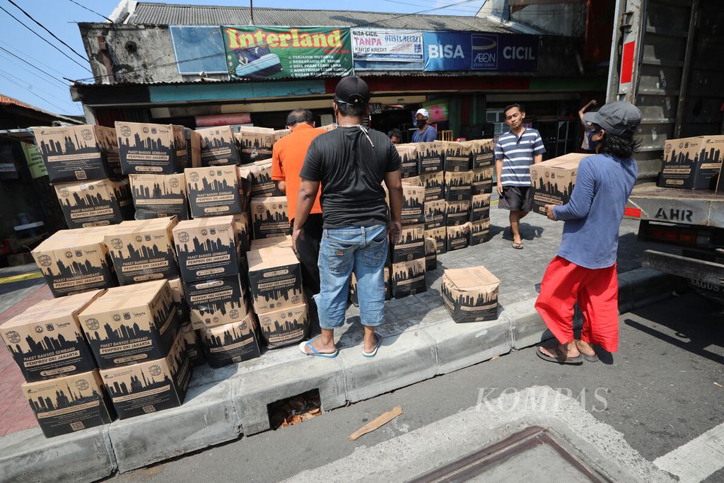 Warga menata kardus bantuan sosial Pemprov DKI yang diturunkan dari truk ekspedisi di Kelurahan Bidara Cina, Kecamatan Jatinegara, Jakarta Timur, Senin (27/7/2020). 