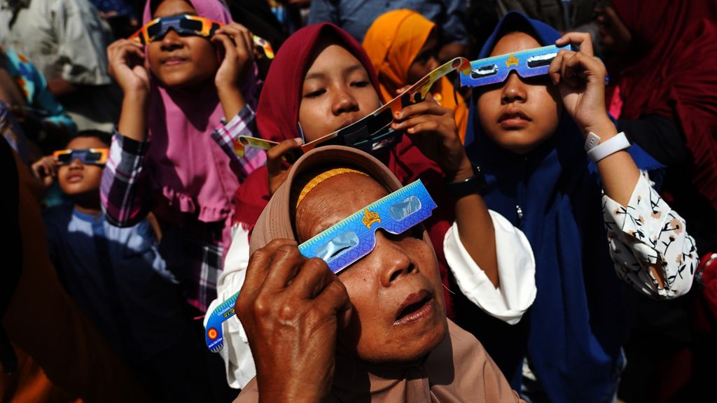 Antusiasme warga menggunakan kacamata gerhana saat melihat gerhana matahari cincin yang teramati di Lapangan Bunsur, Sungai Apit, Kabupaten Siak, Riau, Kamis (26/12/2019). Fenomena gerhana matahari cincin ini disambut antusias masyarakat setempat dan juga berbagai pendatang dari berbagai kota di Indonesia. Sepanjang tahun 2019, gerhana ini merupakan gerhana kedua yang bisa diamati di wilayah Indonesia setelah gerhana bulan sebagian 17 Juli 2019.
