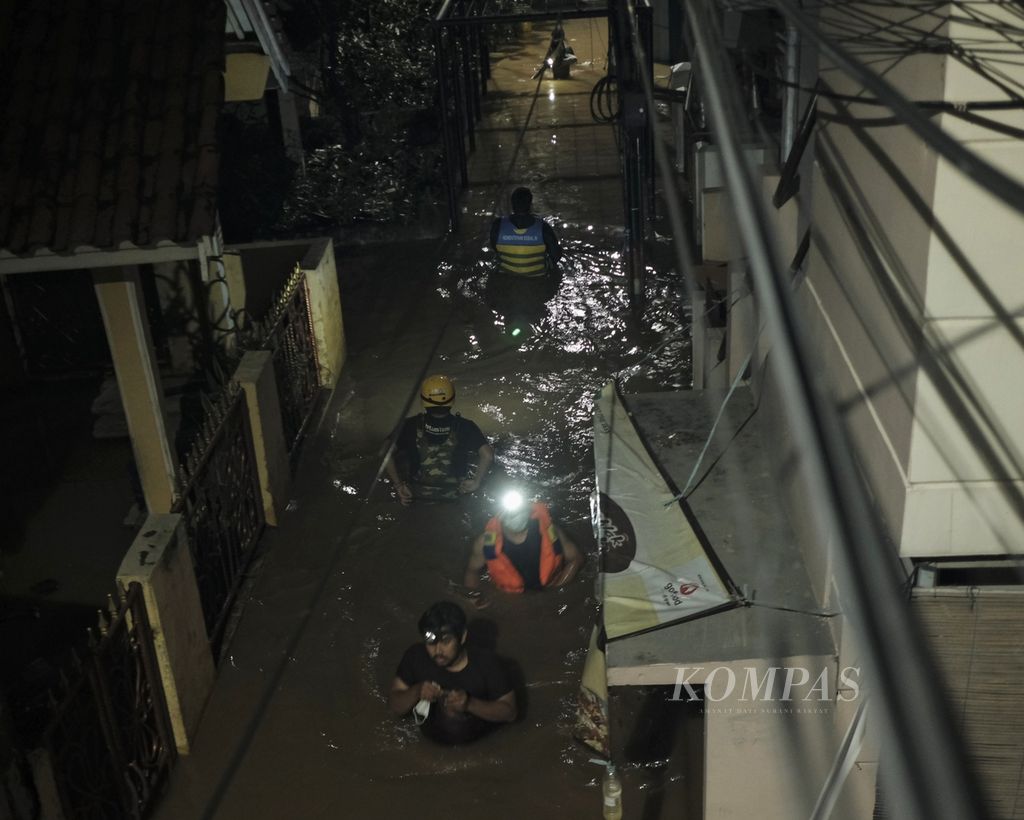 Warga melintasi ruas gang di RW 007 Kampung Melayu, Jatinegara, Jakarta Timur, yang terendam banjir pada Senin (7/2/2021) malam. Banjir pada malam hari itu masih setinggi 60 sentimeter.
