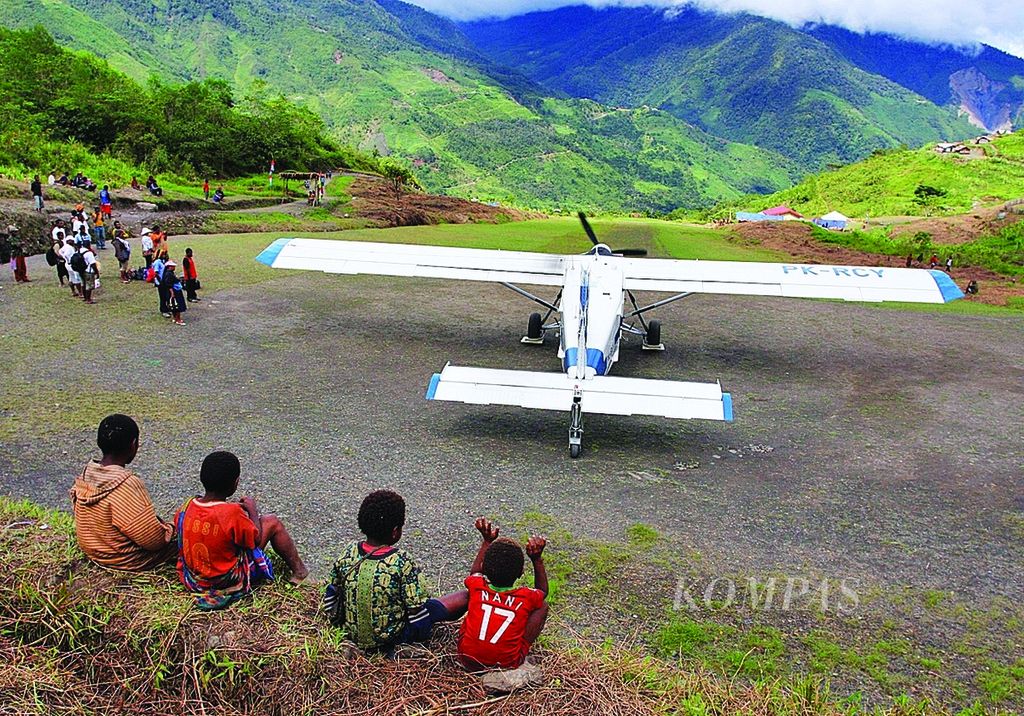 Anak-anak warga Distrik Oklip, Kabupaten Pegunungan Bintang Papua tengah menyaksikan pesawat perintis milik AMA, Selasa (13/12/2011). Pesawat-pesawat perintis seperti itulah yang menjadi penghubung wilayah pedalaman Papua. Hingga saat ini ketergantungan pada armada udara perintis itu di Papua masih tinggi karena kondisi geografis yang berat dan infrastruktur darat yang belum memadai.