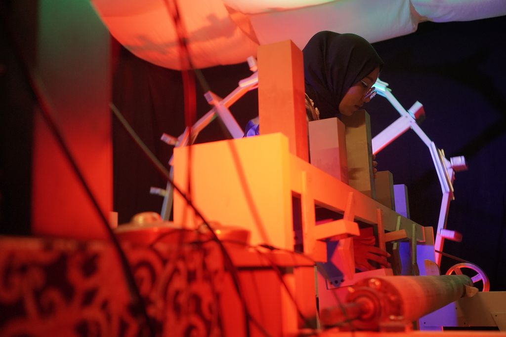 Komposer Rani Jambak membuka kunci alu atau penumbuk instalasi replika kincir air dalam menampilkan karya musik Kincia Aia: Malenong (M)ASO di Rumah Gagas, Nagari Lasi, Kecamatan Candung, Agam, Sumatera Barat, Jumat (22/7/2022) malam. Karya musik eksperimental itu terinspirasi dari teknologi <i>kincia aia</i> atau kincir air Minangkabau yang setidaknya sudah ada sejak 204 tahun silam.