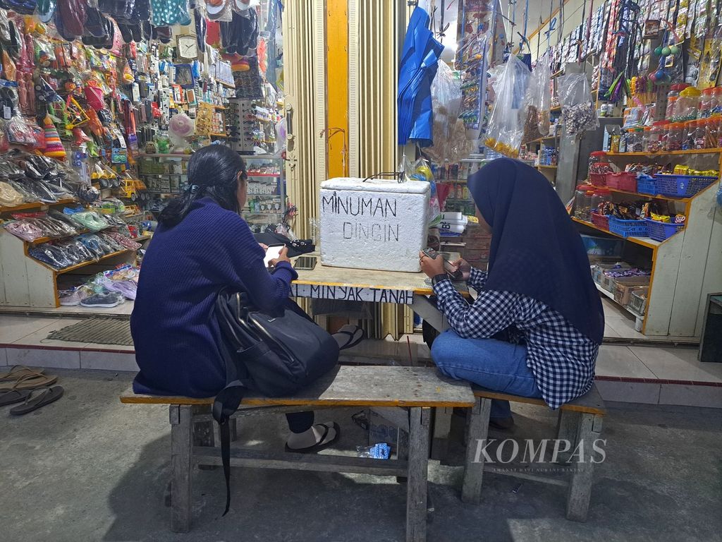 Dua perempuan sedang mengakses <i>Wi-Fi</i> berbayar dari internet satelit untuk urusan pekerjaan di sebuah warung di dermaga Polaga, Desa Sikakap, Kecamatan Sikakap, Kepulauan Mentawai, Sumatera Barat, Rabu (21/6/2023). Wifi berbayar dari internet satelit/radio merupakan satu-satunya cara mengakses internet di Sikakap, pusat perdagangan tertua di Kepulauan Mentawai. 