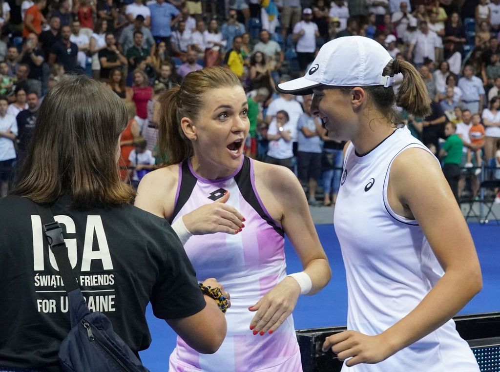 Iga Swiatek (kanan) bergurau dengan mantan petenis Polandia Agnieszka Radwanska (tengah) usai mengikui laga amal bertajuk "Iga Swiatek and Friends for Ukraine" di Krakow, Polandia, 23 Juli 2022,