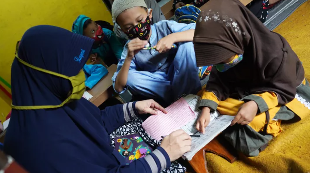 Suasana belajar mengaji di Cibuluh, Bogor Utara, Kota Bogor, Jawa Barat, Senin (7/9/2020). Alifah (42) meneliti tugas menulis huruf arab. Setelah beberapa bulan sempat terhenti, kegiatan belajar mengaji di tempat itu kembali dibuka dengan syarat tetap mewajibkan murid-muridnya mematuhi aturan penggunaan masker sebagai protokol kesehatan.