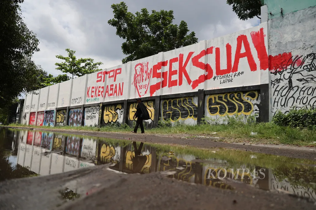 Warga melintas di depan mural berisi seruan untuk mendorong pengesahan Rancangan Undang-Undang Tindak Pidana Kekerasan Seksual yang dibuat di tembok Stadion Kridosono, Yogyakarta, Senin (10/1/2021). Berbagai elemen masyarakat terus menyuarakan urgensi pengesahan RUU TPKS melalui bermacam media seiring terus berulangnya kemunculan kasus kekerasan seksual, terutama terhadap perempuan dan anak-anak.