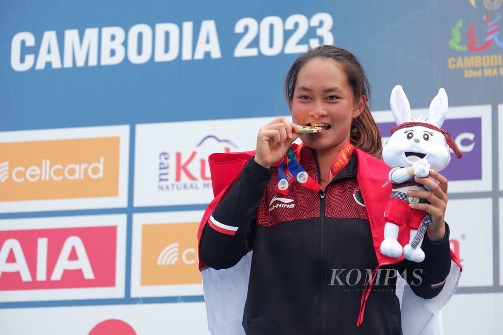 Petenis putri Indonesia, Priska Madelyn Nugroho, menggigit medali emas yang berhasil dia menangi di nomor tunggal putri SEA Games Kamboja 2023 setelah pengalungan medali di Lapangan Tenis Kompleks Olahraga Morodok Techo, Phnom Penh, Sabtu (13/5/2023). Terakhir kali petenis putri Indonesia memenangi nomor tunggal adalah di SEA Games Filipina 2019 atas nama Aldila Sutjiadi.