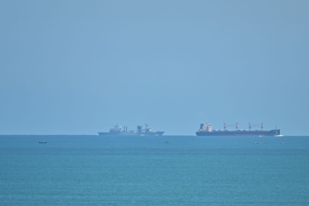 Tampak di kejauhan sebuah kapal perang China (kiri) berpatroli tak jauh dari Pulau Pingtan, salah satu pulau terluar China yang paling dekat dengan wilayah teritorial Taiwan, Jumat (5/8/2022). Latihan militer China di sekeliling wilayah perairan Taiwan dikhawatirkan berdampak pada perekonomian global. (Photo by Hector RETAMAL / AFP)