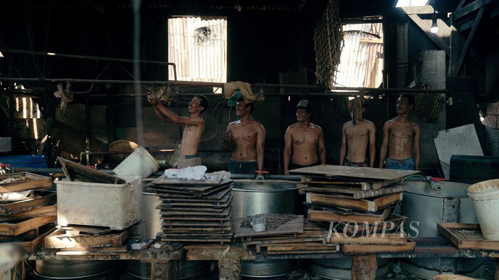 Para pembuat tahu berswafoto saat mogok produksi tahu di industri rumah tangga pembuatan tahu di Pondok Kelapa, Duren Sawit, Jakarta Timur, Selasa (22/2/2022). Produsen tahu di tempat tersebut mogok produksi memasuki hari kedua terkait tingginya harga kedelai impor di pasaran. Harga kedelai impor naik dari Rp 8.500 per kilogram menjadi Rp 12.000 per kilogram.