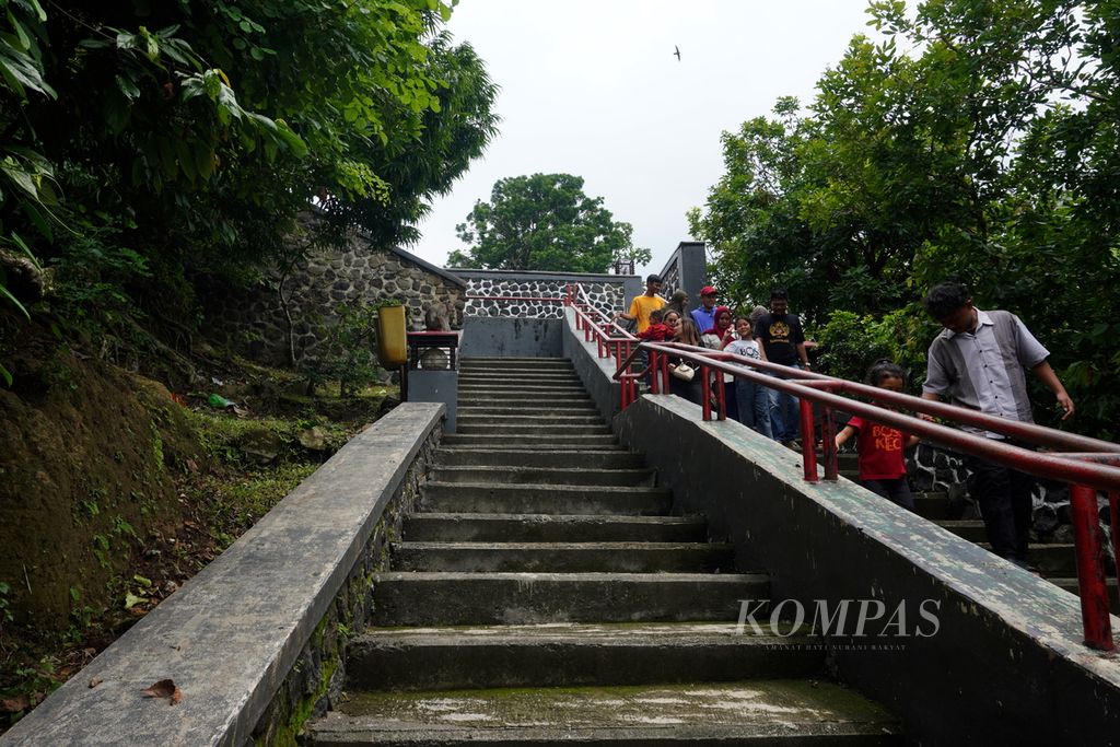 Seekor monyet beraktivitas di sekitar wisatawan yang melintas saat berkunjung ke Goa Kreo, Kecamatan Gunungpati, Kota Semarang, Jawa Tengah, Minggu (29/12/2024). Ratusan wisatawan dari Semarang dan sekitarnya berkunjung ke Goa Kreo setiap harinya. Mereka ingin mengisi waktu libur akhir tahun mereka dengan menikmati keindahan alam Goa Kreo dan berinteraksi dengan monyet penghuni Goa Kreo. 