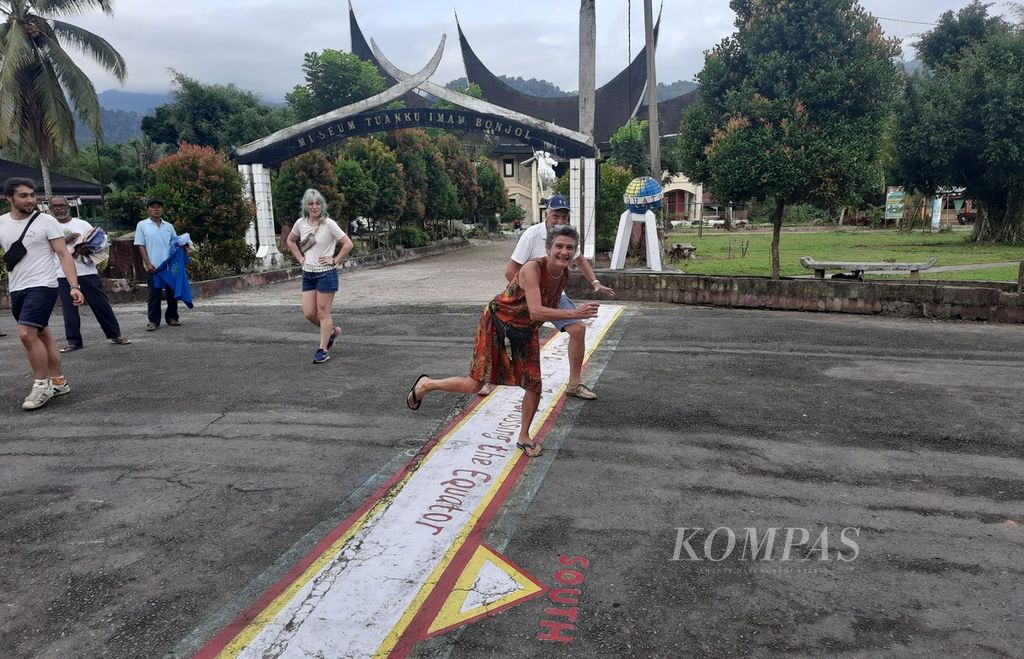 Turis mancanegara berpose di garis ekuator kawasan Monumen Ekuator di Nagari Ganggo Mudiak, Kecamatan Bonjol, Pasaman, Sumatera Barat, Senin (5/9/2022). Kawasan yang dilintasi garis khatulistiwa yang membelah Bumi jadi bagian utara dan selatan ini merupakan ikon wisata Pasaman.