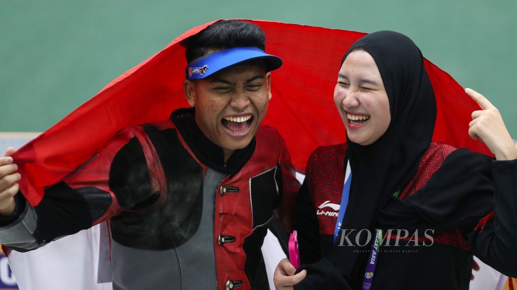 Atlet menembak Indonesia, Fathur Gustafian (kiri), di samping kekasihnya yang juga atlet menembak, Dewi Laila Mubarokah, merayakan keberhasilan meraih medali emas nomor 10 meter senapan angin individu putra cabang menembak SEA Games Vietnam 2021 di Sport Training Center Hanoi, Hanoi, Vietnam, Selasa (17/5/2022). Dewi sebelumnya juga meraih emas.