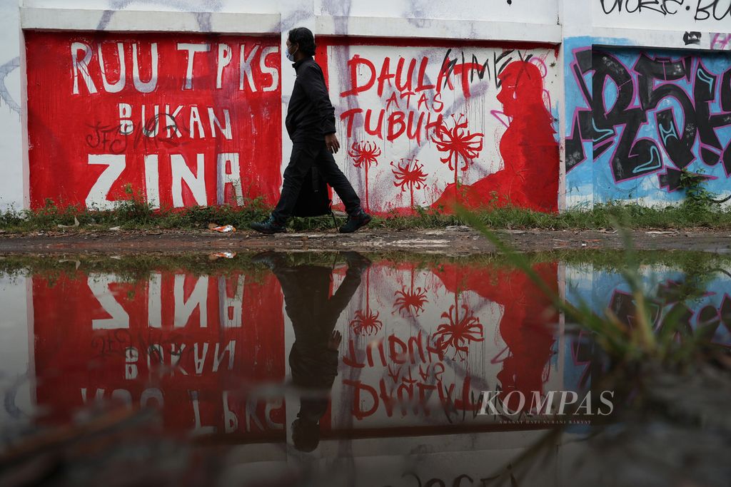 Warga melintas di depan mural berisi seruan untuk mendorong pengesahan Rancangan Undang-Undang Tindak Pidana Kekerasan Seksual yang dibuat di tembok Stadion Kridosono, Yogyakarta, Senin (10/1/2021). Berbagai elemen masyarakat terus menyuarakan urgensi pengesahan RUU TPKS melalui bermacam media seiring terus berulangnya kemunculan kasus kekerasan seksual, terutama terhadap perempuan dan anak-anak.