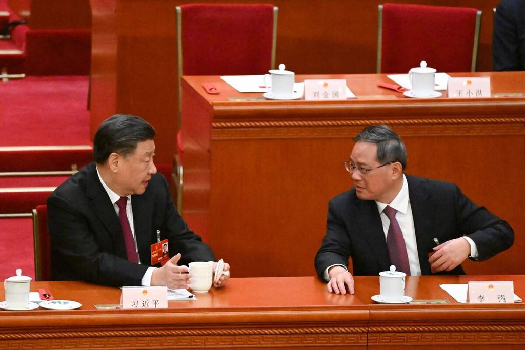 Presiden China Xi Jinping (kiri) berbicara dengan Li Qiang dalam sesi pleno sidang Kongres Rakyat Nasional di Aula Besar Rakyat, Beijing, 10 Maret 2023.