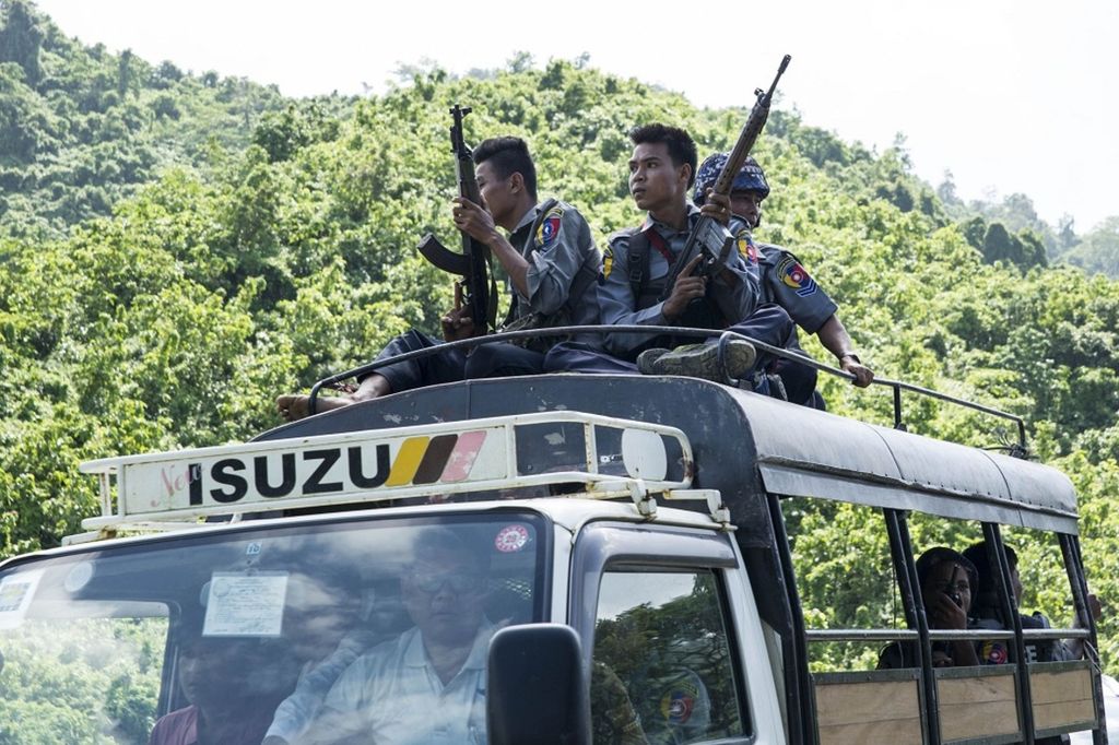 Polisi Myanmar duduk di atap truk saat mereka mengawal staf Perserikatan Bangsa-Bangsa (PBB) dan lembaga-lembaga swadaya asing dalam kunjungan ke area konflik, di pos pemeriksaan dekat gerbang masuk ke Kota Maungdaw, Negara Bagian Rakhine, Myanmar, 28 Agustus 2017.