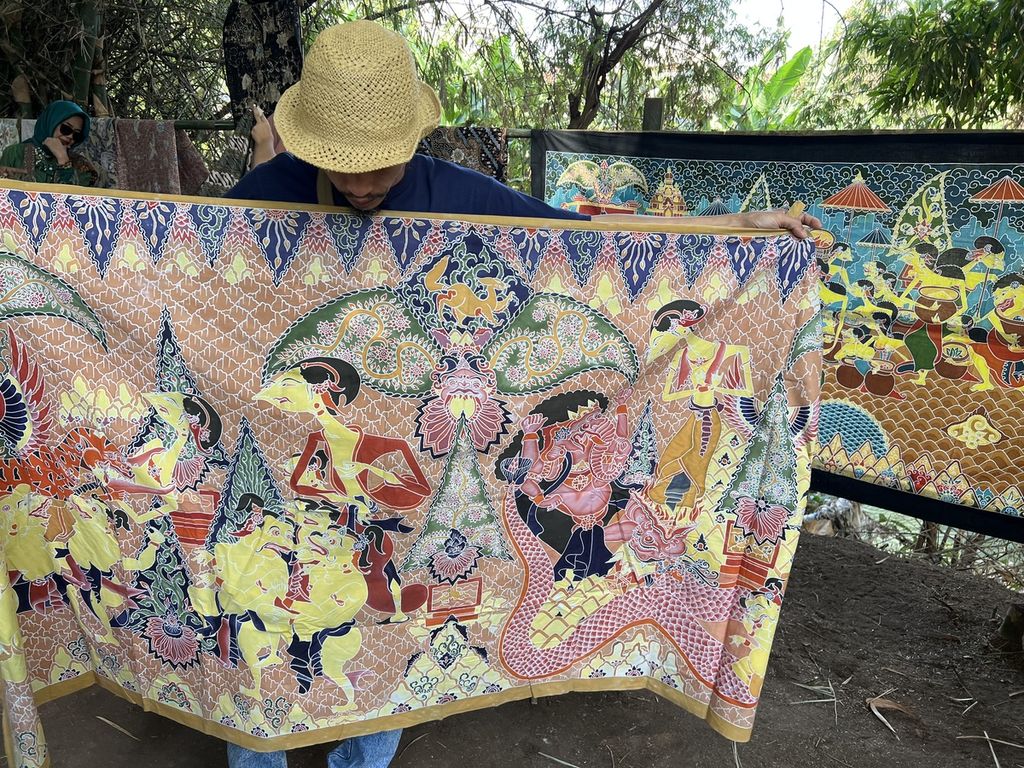 Farid (47) menggelar karya batik lukis klasik wayang beber, di Pasar Barongan Kali Gunting, Desa Mojotrisno, Kecamatan Mojoagung, Kabupaten Jombang, Sabtu (6/8/2022).