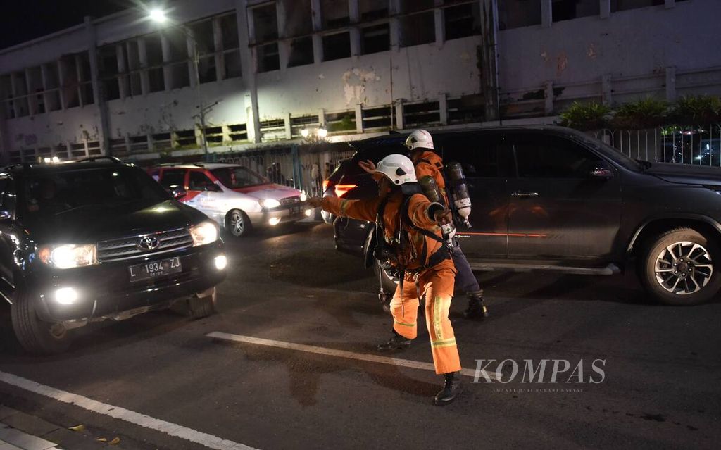 Petugas berusaha mencari jalan saat kemacetan lalu lintas agar truk pemadam kebakaran bisa lewat menuju lokasi kebakaran Tunjungan Plaza di Kota Surabaya, Jawa Timur, Rabu (13/4/2022). Api pertama kali terlihat di Tunjungan Plaza 5 pada pukul 17.40 WIB. Sebanyak 20 truk pemadam kebakaran, termasuk di dalamnya tiga <i>sky lift</i>, dikerahkan untuk memadamkan api. Kejadian yang membuat Jalan Embong Malang ditutup itu tidak menimbulkan korban jiwa.