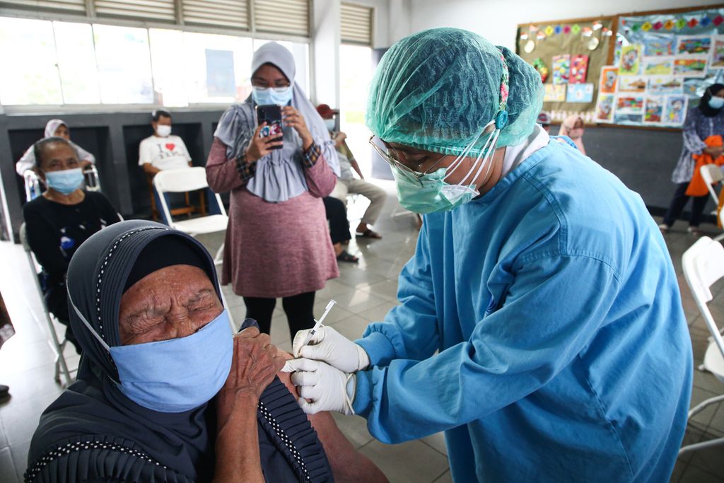 Petugas vaksinator menyuntikkan vaksin Covid-19 dosis pertama ke warga lansia di Sekolah Cinta Kasih Tzu Chi, Cengkareng, Jakarta Barat, Rabu (24/2/2021).  Vaksinasi massal bagi warga lansia ini menyasar para penghuni rumah susun Tzu Chi. 