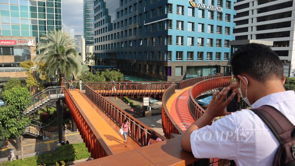 Seorang warga memotret jembatan penyeberangan orang dari anjungan pandang Jembatan Phinisi di Jalan Sudirman, Jakarta Pusat, Rabu (6/4/2022) sore.