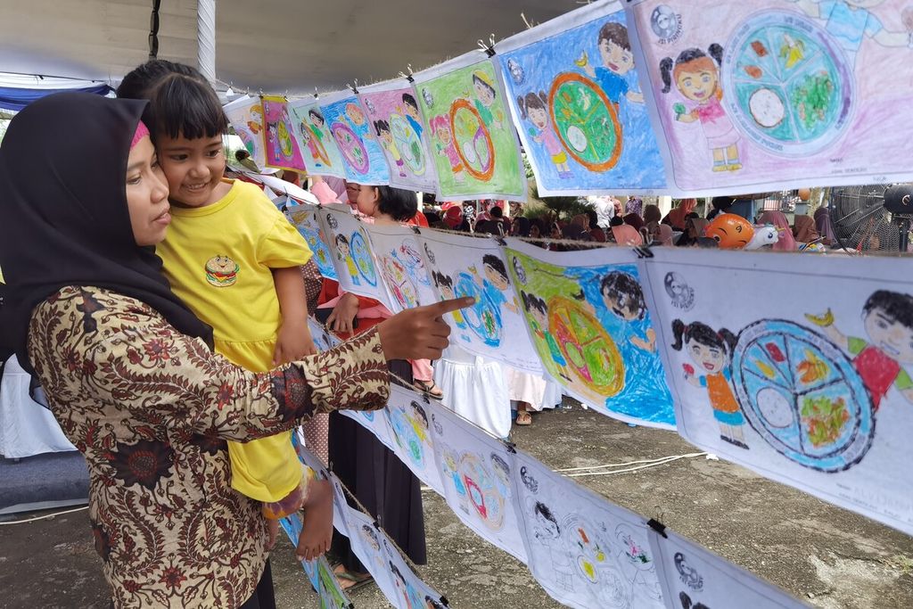 Seorang ibu mengajak putrinya melihat karya peserta Lomba Mewarnai Isi Piringku dalam rangkaian program Aksi Gizi Generasi Maju yang diselenggarakan Danone Indonesia, di Pasar Seni Banyumulek, Kabupaten Lombok Barat, NTB, Kamis (9/2/2023).