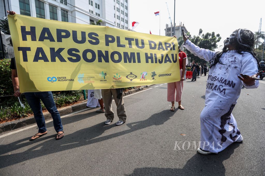 Peserta aksi membentangkan spanduk berisi pesan aksi di depan kantor Otoritas Jasa Keuangan (OJK) Gedung Sumitro Djojohadikusumo, Jakarta, Jumat (15/9/2023). Peserta aksi yang tergabung ke dalam Koalisi Setara atau Selamatkan Kalimantan Utara melakukan aksi teatrikal menolak rencana OJK memasukkan PLTU kawasan industri dalam taksonomi hijau atau pembiayaan hijau. 