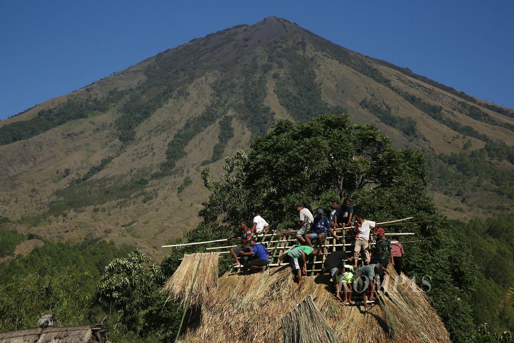 Warga kampung adat Bena bergotong royong memasang atap rumah suku Kopa dengan latar belakang Gunung Inerie di Desa Tiworiwu, Kecamatan Jerebu'u, Kabupaten Ngada, Nusa Tenggara Timur, Senin (5/8/2019).