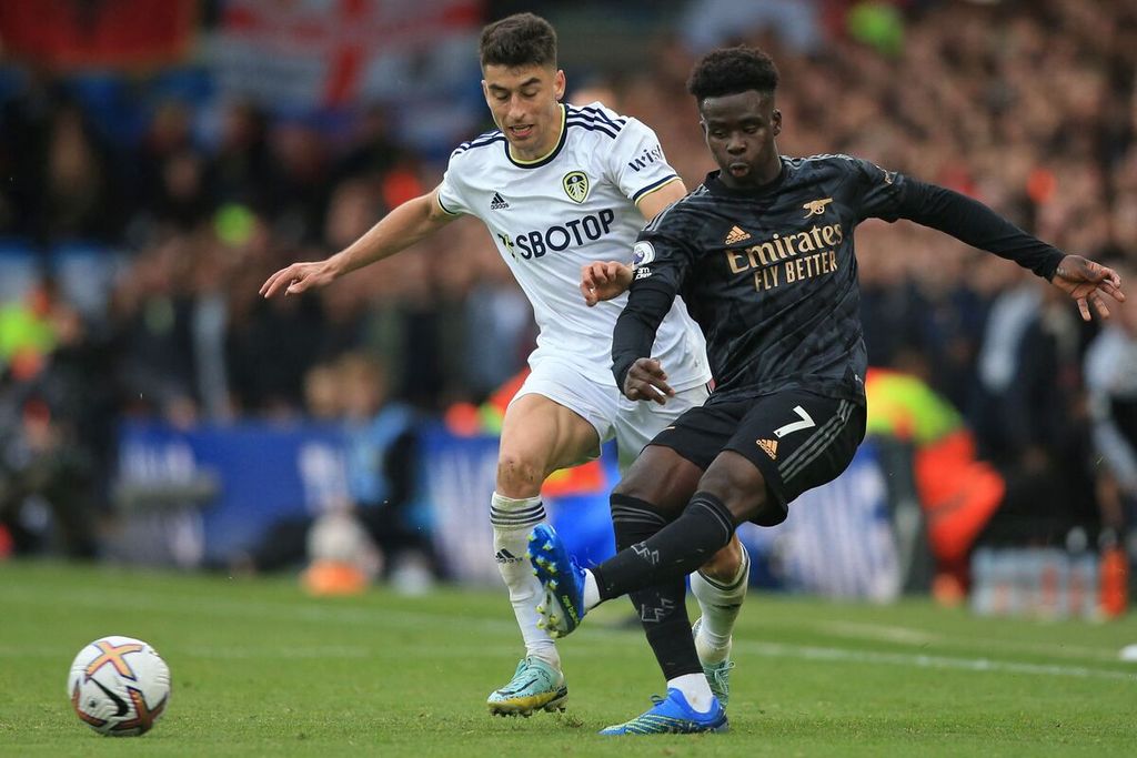 Gelandang Leeds United, Marc Rocca (kiri), dan penyerang sayap Arsenal Bukayo Saka mengejar bola dalam pertandingan Liga Inggris antara Leeds United dan Arsenal di Stadion Elland Road, Leeds, Minggu (16/10/2022). Arsenal menang atas Leeds, 1-0.