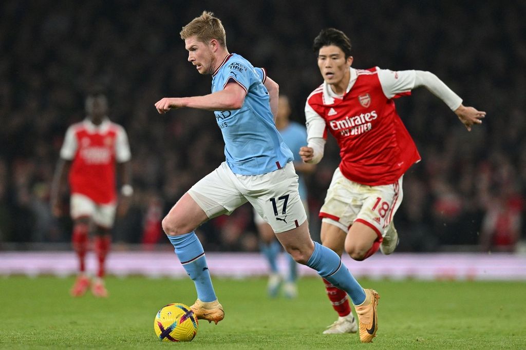 Gelandang Manchester City, Kevin De Bruyne (tengah), mengontrol bola setelah merebutnya dari pemain Arsenal, Takehiro Tomiyasu, pada laga Liga Inggris di Stadion Emirates, London, Kamis (16/2/2023) dini hari WIB. Pada laga itu, City menang 3-1 dan de Bruyne mencetak satu gol.