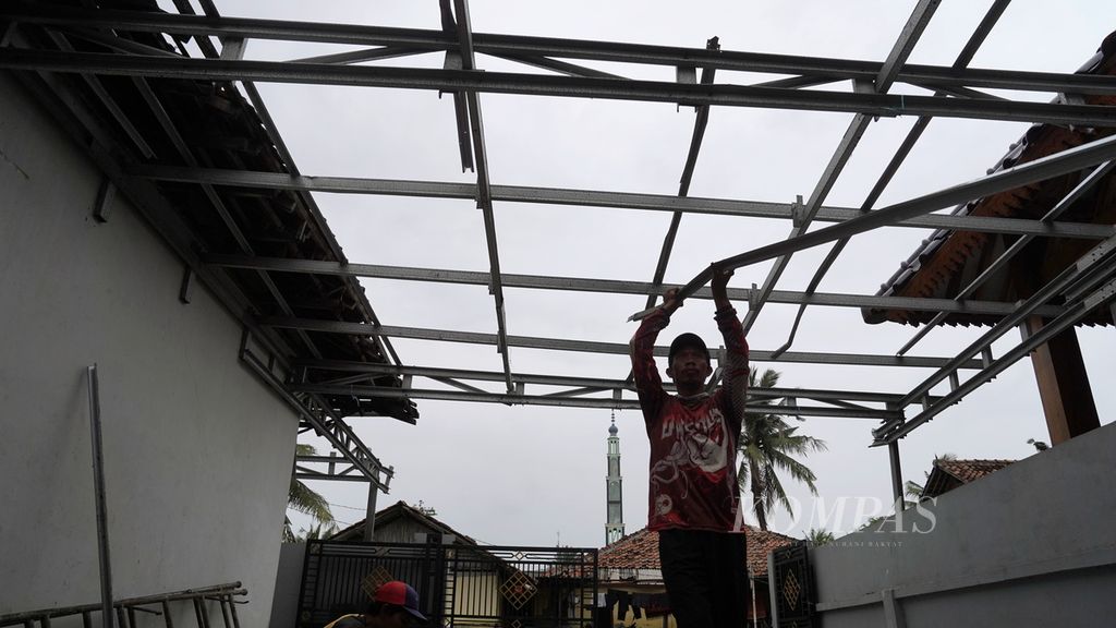 Warga memperbaiki atap baja ringan rumahnya yang hancur diterjang angin kencang di Kampung Pulo Damar Kidul, Desa Sukawijaya, Kecamatan Tambelang, Kabupaten Bekasi, Jawa Barat, Minggu (12/2/2023). Sekitar 50 rumah rusak ringan hingga parah di Kecamatan Tambelang dan Kecamatan Sukakarya, Bekasi, Jumat (10/2/2023) malam, akibat terjangan angin kencang yang disertai hujan deras. Keberadaan siklon tropis Freddy memberi dampak tidak langsung dengan meningkatnya intensitas hujan dan angin kencang di sejumlah daerah di Pulau Jawa dalam beberapa hari terakhir. 