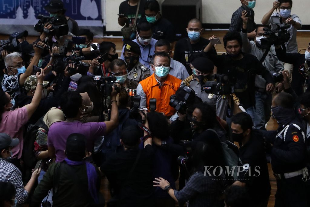 Menteri Perikanan dan Kelautan Edhy Prabowo (mengenakan rompi tahanan) dikerubuti wartawan saat meninggalkan tempat jumpa pers yang digelar Komisi Pemberantasan Korupsi terkait kasus kasus dugaan suap perizinan budidaya lobster tahun 2020 di Gedung KPK, Jakarta, Kamis (26/11/2020) dini hari.