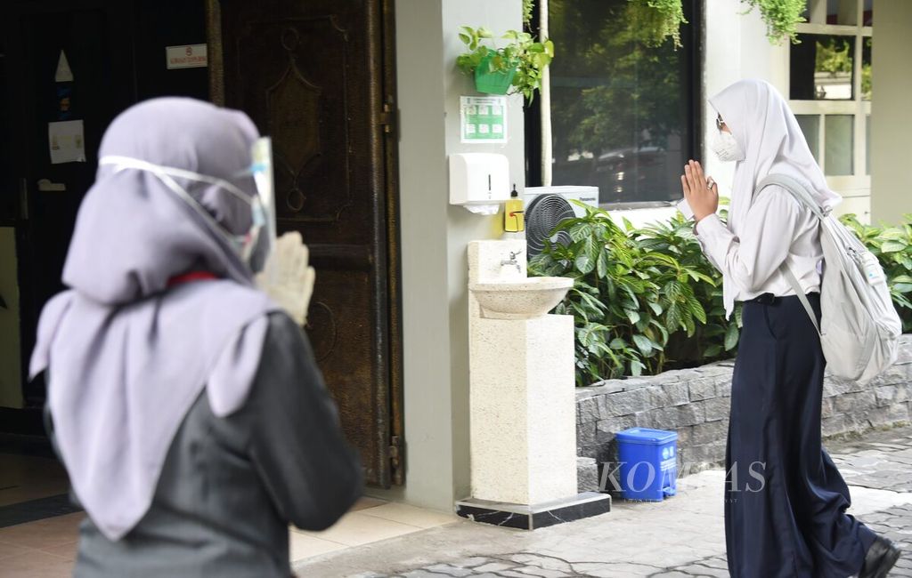 Siswa memberi hormat dari jauh kepada guru saat tiba di sekolah ketika berlangsung simulasi pembelajaran tatap muka di SMP Negeri 1 Surabaya, Surabaya, Jawa Timur, Selasa (12/8/2020). Bagi siswa dan guru yang hadir diberlakukan protokol kesehatan yang ketat. Kagiatan yang berlangsung untuk mengujicoba sistem yang akan dilakukan saat nanti pembelajaran tatap muka diberlakukan di tengah pandemi.