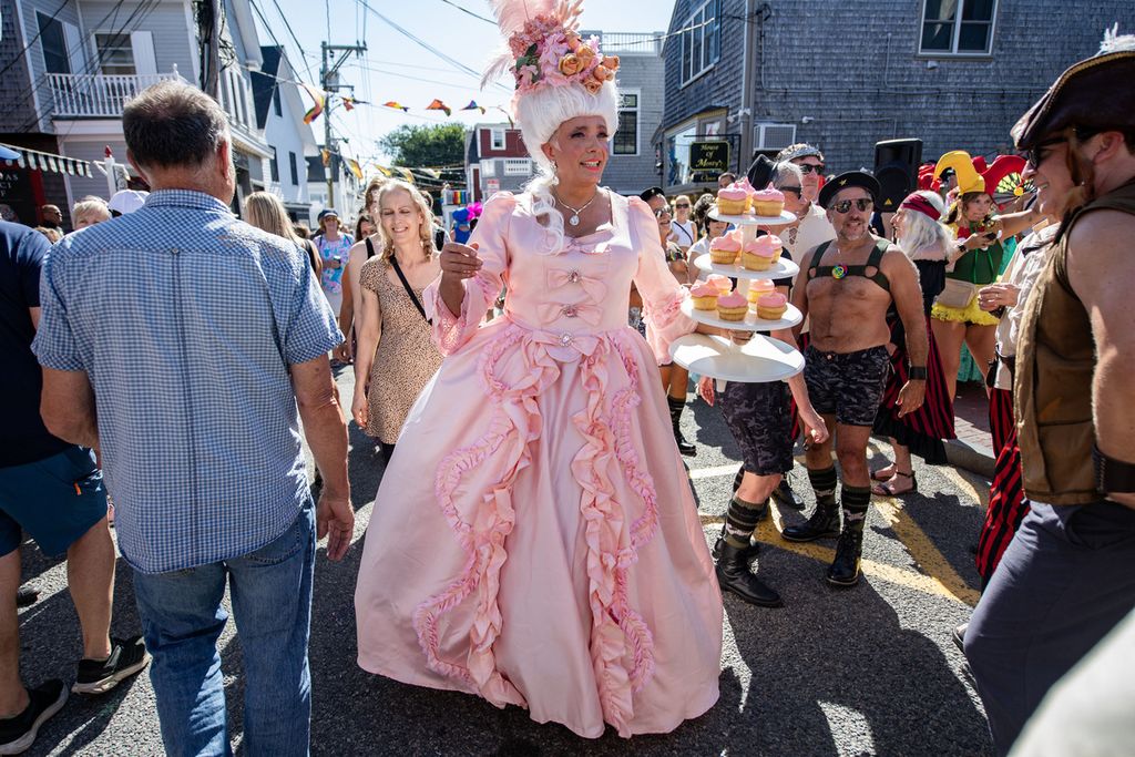 Seorang perempuan berpakaian ala Marie Antoinette menari dengan tumpukan kue di tangan kiri dalam acara Karnaval Ke-46 Provincetown di Provincetown, Massachusetts, AS, 22 Agustus 2024. 