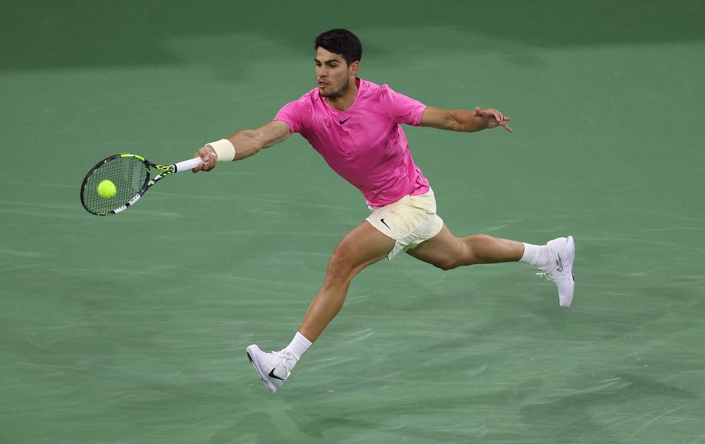 Petenis Spanyol Carlos Alcaraz mengembalikan bola ke petenis Inggris Jack Draper dalam laga ATP Masters 1000 Indian Wells di Indian Wells, California, Selasa (14/3/2023). Draper menyerah karena cedera pada laga itu. 